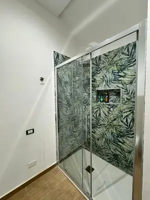 a shower with a green leaf pattern on the wall at Sicilia biedda casa vacanze in Terrasini