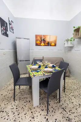 a dining room table with chairs and a table and a refrigerator at Gioiello di casa in Palermo