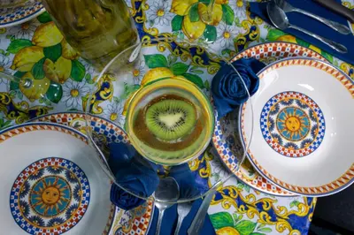 a table with plates and a cup of kiwi juice at Gioiello di casa in Palermo