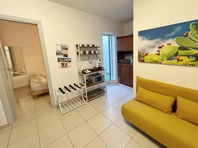 a living room with a yellow couch and a kitchen at A Casa Tua Palermo in Palermo
