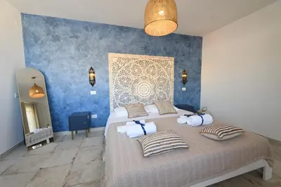 a bedroom with a bed with pillows and a blue wall at Riad Casa Vacanze in Terrasini
