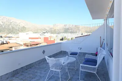 a balcony with chairs and tables and a view of a city at Riad Casa Vacanze in Terrasini