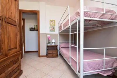 a bedroom with two bunk beds with pink sheets at Casa Carini - Villa Vacanze sul Mare con piscina idromassaggio in Carini