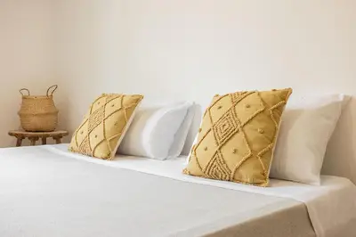 a bed with white sheets and gold pillows on it at Casa Marinù in Palermo