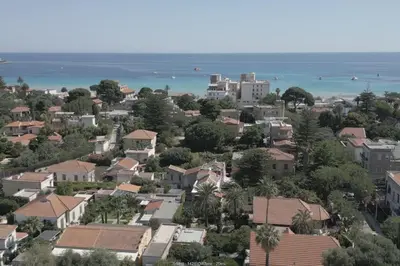 a town with houses and the ocean in the background at apartment by the sea Mondello beach in Palermo