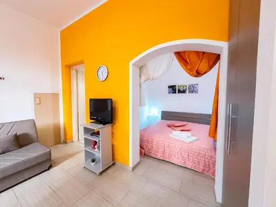 a bedroom with a bed and a tv and a couch at Appartamenti Bellini in Castellammare del Golfo