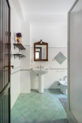 a white bathroom with a sink and a mirror at Le Casette all'Addaura by Domus Sicily in Mondello