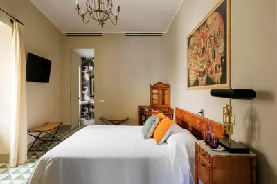 a bedroom with a large white bed and a chandelier at Trinacria Luxury Suite in Palermo