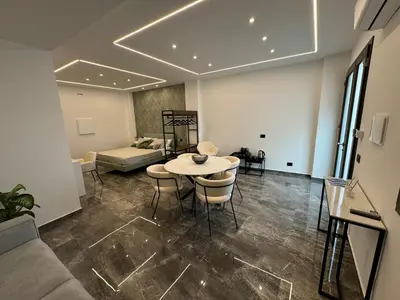 a living room with a table and chairs and a couch at GRA' Suite Deluxe in Terrasini