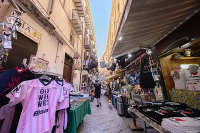 a woman walking through a market with clothes and merchandise at Vista San Domenico in Palermo