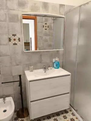 a bathroom with a sink and a toilet and a mirror at Home For You in Carini