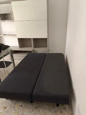 a black bed in a room with a chair at Home For You in Carini