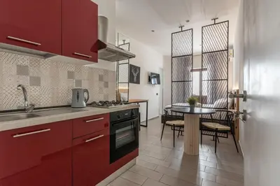 a kitchen with red cabinets and a table with chairs at Naos Home - Alle Spalle del Teatro Massimo in Palermo