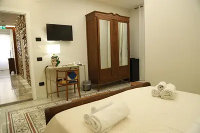 a bedroom with a bed and a television and towels at LE TRE NINFE Cinisi in Cinisi