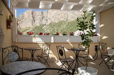 a room with tables and chairs and a window with a mountain at LE TRE NINFE Cinisi in Cinisi