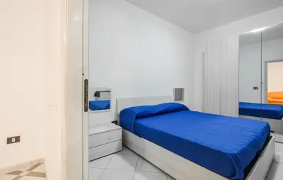a white bedroom with a blue bed and a mirror at Lovely Apartment In Casteldaccia in Casteldaccia