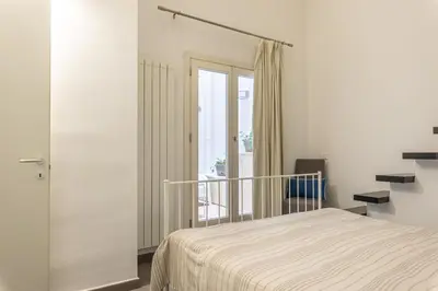 a white bedroom with a bed and a balcony at MetaM Apartment in the City Center by Wonderful Italy in Palermo