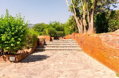 a brick retaining wall with stairs and a tree at Casa Giulù- in Palermo