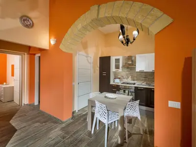 a kitchen with an orange wall and a table and chairs at Villa Mari e Monti by Interhome in Castellammare del Golfo