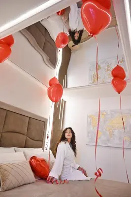 a woman sitting on a bed with red balloons at Raquel suite and SPA in Palermo