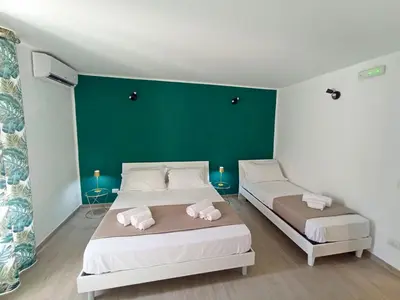 two beds in a room with a green wall at Mille Memories Apartment in Palermo