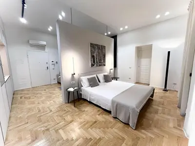 a bedroom with a white bed and a wooden floor at Palazzo Giglio suite in Palermo