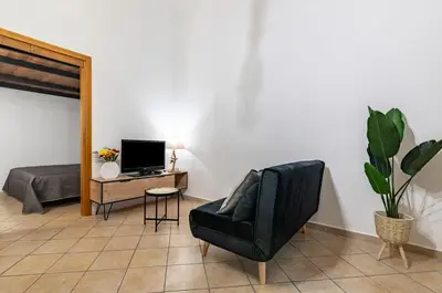 a living room with a black leather chair and a television at GuestHost - Your Home at the Cathedral - Palermo Cozy Flat in Palermo
