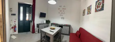 a small dining room with a table and a red chair at Alfa & Omega apartments in Palermo