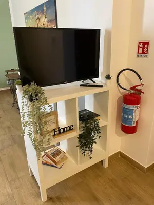 a tv on a white stand with a tv at Dai Palermitani Rooms & Apartments in Palermo