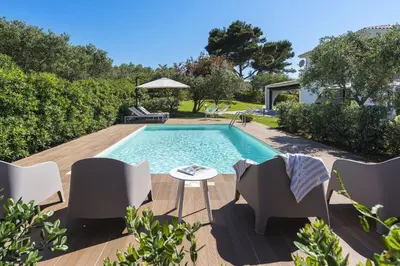 a swimming pool in a backyard with chairs and a table at Villa Perla Di Guidaloca in Scopello