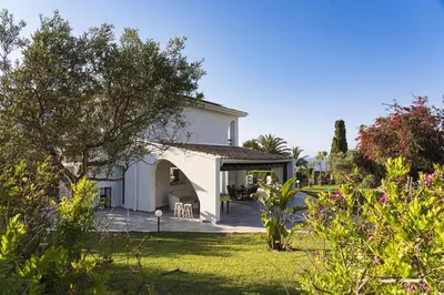 a white house with a yard with flowers at Villa Perla Di Guidaloca in Scopello