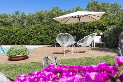 two white chairs and an umbrella next to a pool at Villa Perla Di Guidaloca in Scopello