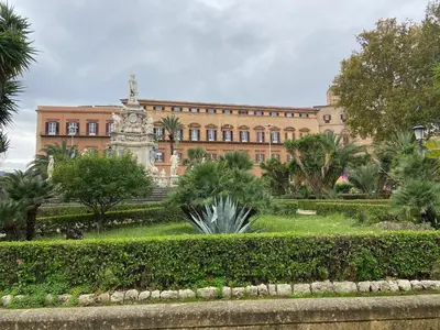 a building with a clock tower in front of a garden at Orleans Apartment in Palermo