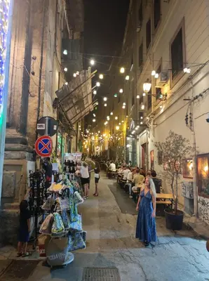 a group of people walking down a street at night at La dimora di Elma in Palermo