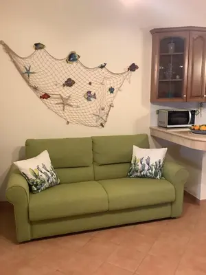 a green couch in a living room with a kitchen at Macari House in Macari