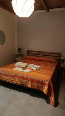 a bedroom with a bed with orange sheets and towels at Domus Case Vacanze civico del mare in Castellammare del Golfo