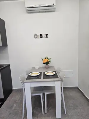 a table with white chairs and a white wall at Flowers Apartments in Marineo