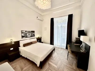 a bedroom with a bed and a desk and a window at Casa O'Tama in Palermo