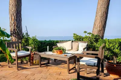 a table and two chairs and a couch on a patio at Alle due Torri, villa sulla roccia a picco sul mare in Altavilla Milicia