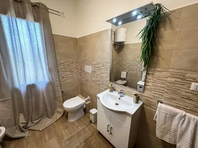 a bathroom with a sink and a toilet and a mirror at Intero Appartamento con Terrazza - Villa Ciaculli in Palermo