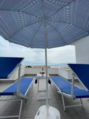 a blue umbrella on a balcony with a table and chairs at Casa Vacanze Villa Lena in Santa Flavia