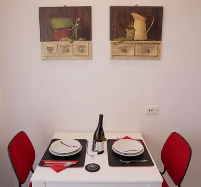 a white table with red chairs and a bottle of wine at Nothotel delle Rose in Palermo