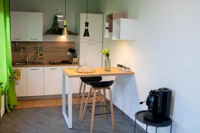 a kitchen with white cabinets and a table with a chair at Intero Appartamento con Solarium - Villa Ciaculli in Palermo