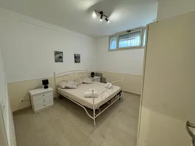 a white bedroom with a bed and a window at Mondello Telemaco Beach in Palermo