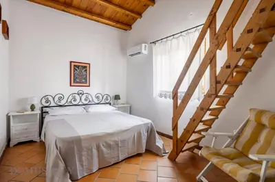 a bedroom with a white bed and a staircase at La Gurra Tenuta Migliore By DomuSicily in Chiusa Sclafani