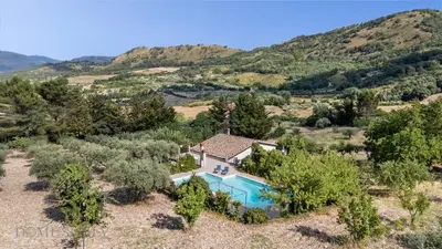 an aerial view of a villa with a swimming pool and a mountain at La Gurra Tenuta Migliore By DomuSicily in Chiusa Sclafani