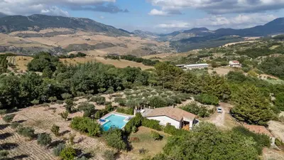 an aerial view of a villa with a swimming pool in a valley at La Gurra Tenuta Migliore By DomuSicily in Chiusa Sclafani