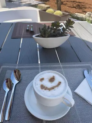 a cup of cappuccino sitting on a table at Olea in Castelluzzo