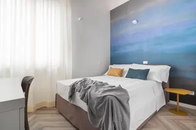 a bedroom with a large bed with a blue wall at La Terrazza su Dante Rooms in Palermo