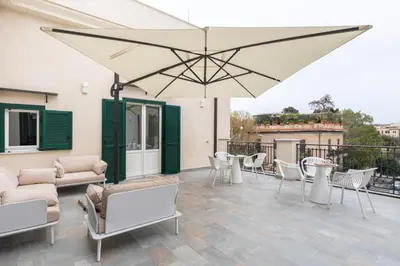 a patio with chairs and tables and a large umbrella at La Terrazza su Dante Rooms in Palermo